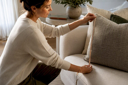 Decorator measuring throw pillow on sofa