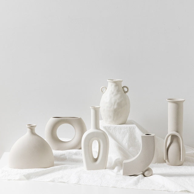 Collection of various white ceramic vases on a light surface with a plain background