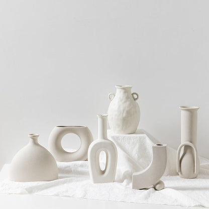 Collection of various white ceramic vases on a light surface with a plain background